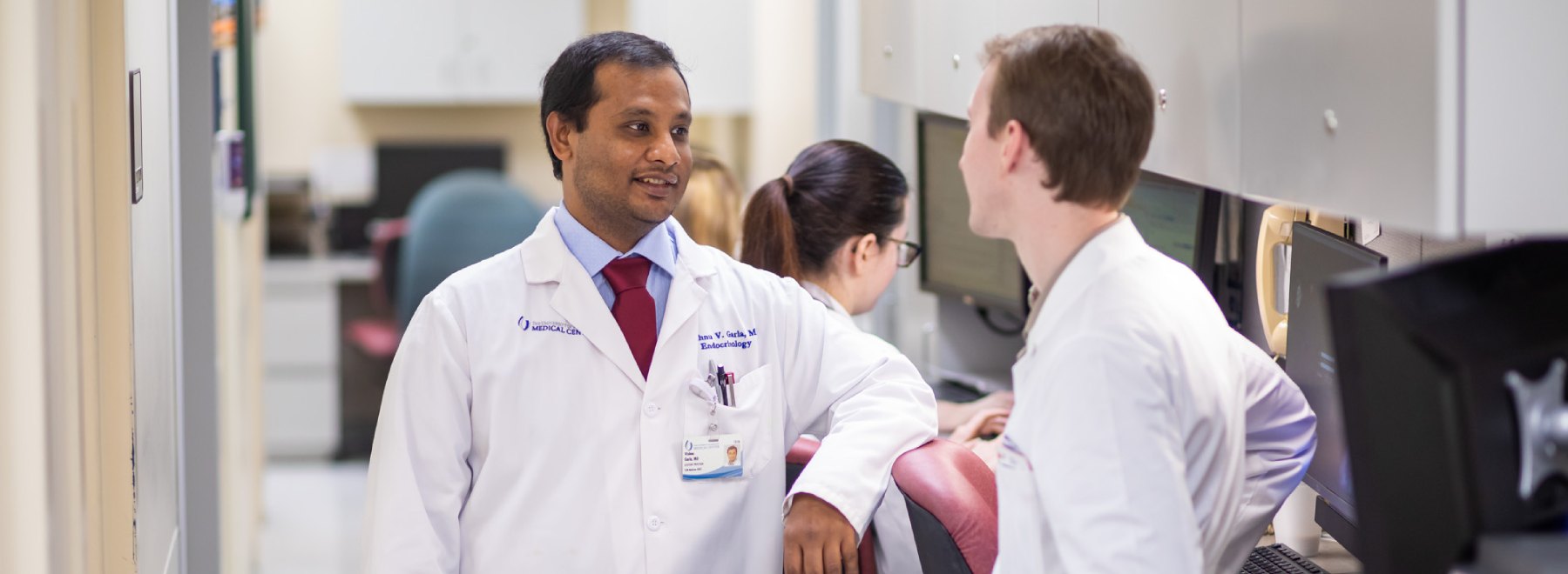 Two male physicians talk in hallway.